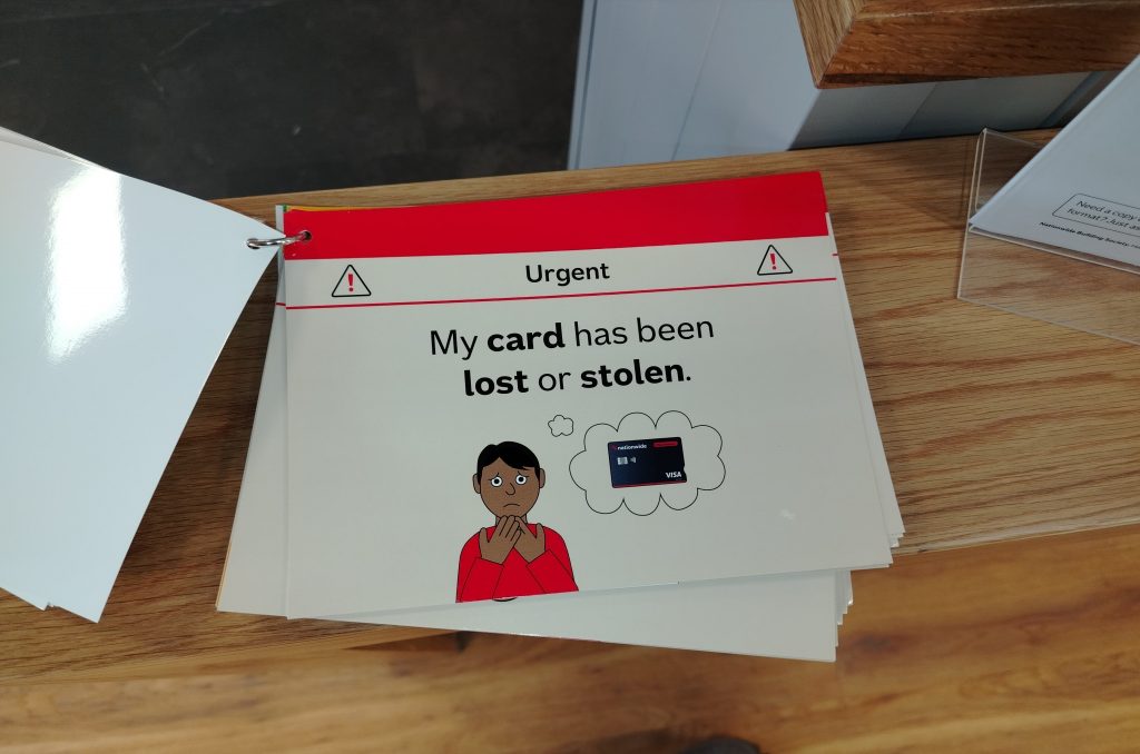 Communication card at a bank.  The top is red and underneath that is the word "urgent".  The main text reads My card has been lost or stolen and there is a picture of a brown-skinned person looking worried with thought bubbles containing a picture of a Nationwide bank card